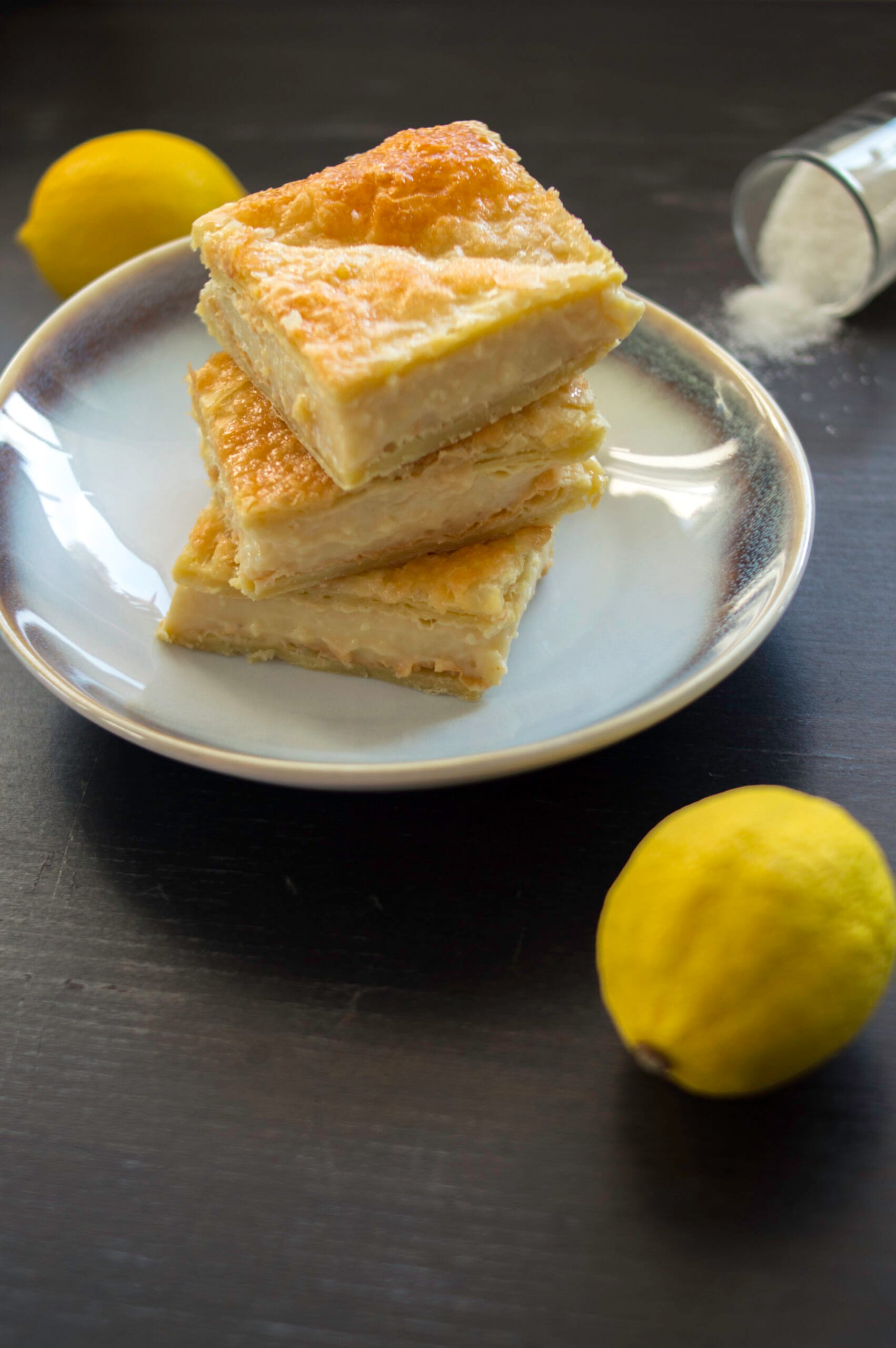 Creamy lemon milk cream bars layered with puff pastry, cut into squares and dusted with sugar