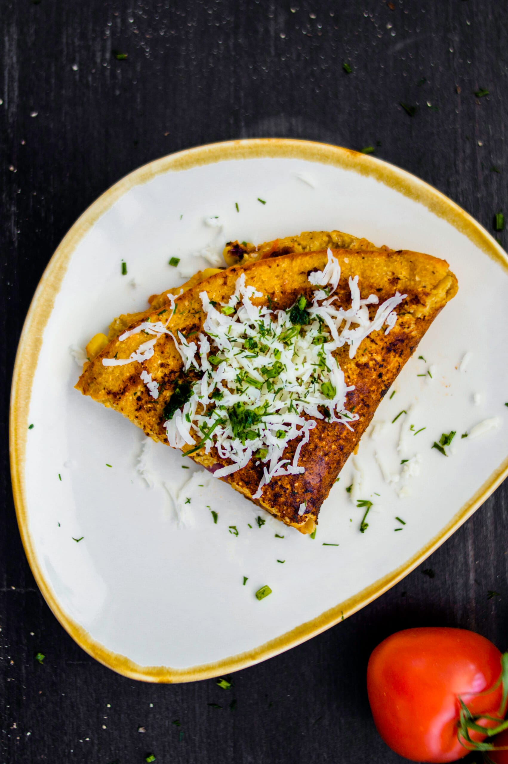 Sliced vegan chickpea omelette on a plate with herbs and side salad