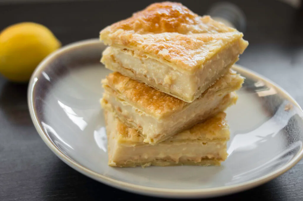 Creamy lemon milk bars layered with puff pastry, cut into squares and dusted with sugar