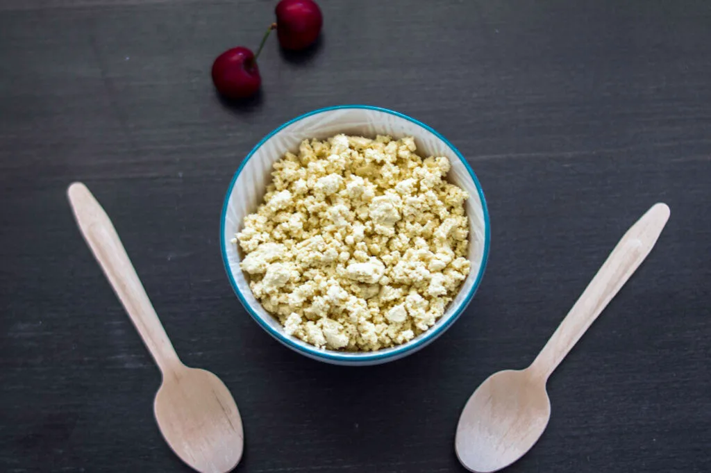 Creamy vegan cottage cheese made with tofu served in a white bowl with a sprinkle of herbs