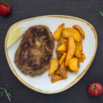 Crispy golden vegan schnitzels served with fries and lemon wedges on a rustic plate