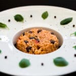 Bowl of creamy risotto alla caprese with tomatoes, pesto, and herbs served warm