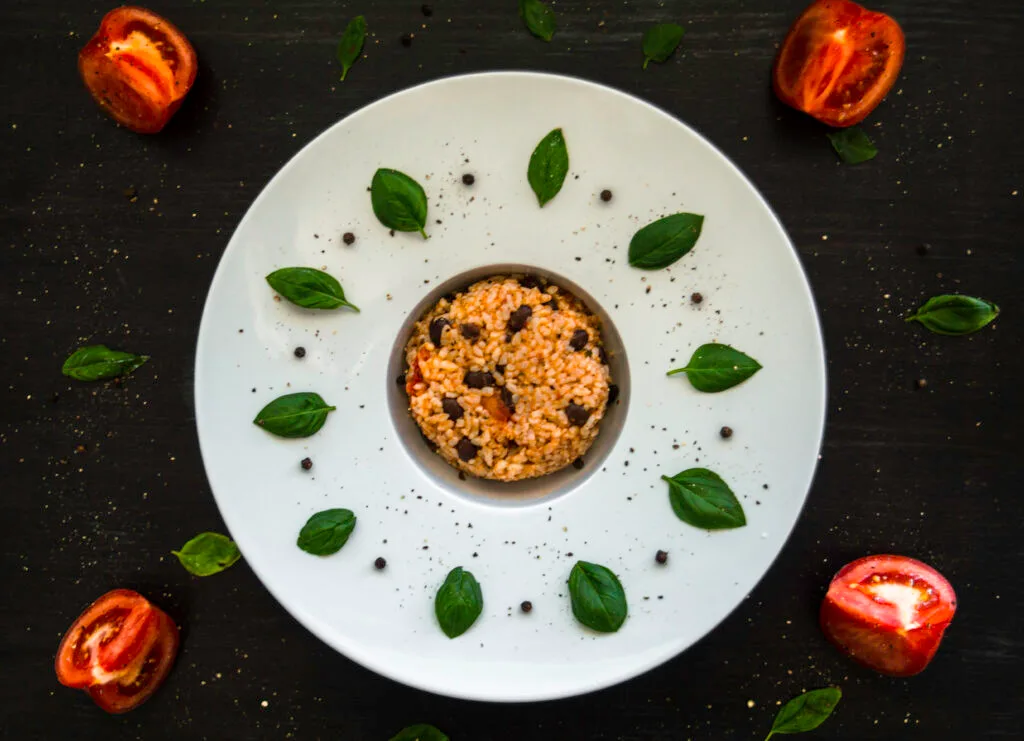 Bowl of creamy risotto alla caprese with tomatoes, pesto, and herbs served warm