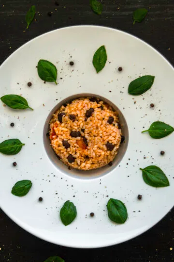 Bowl of creamy risotto alla caprese with tomatoes, pesto, and herbs served warm