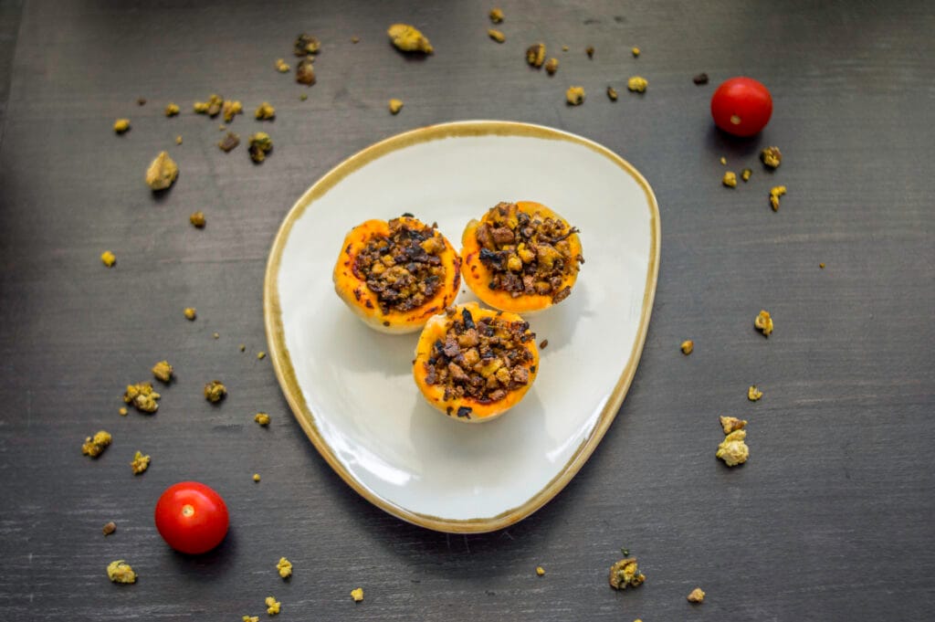 Baked vegan pizza-tofu baskets in muffin tin, topped with herbs and tomato sauce