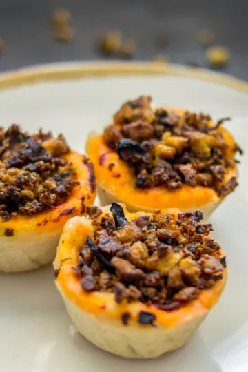 Baked vegan pizza-tofu baskets in muffin tin, topped with herbs and tomato sauce