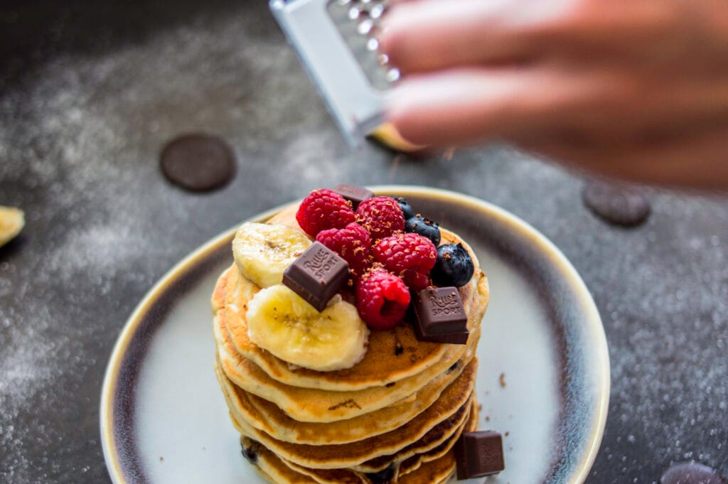 Stack of fluffy banana-chocolate chip pancakes topped with syrup and banana slices on a plate