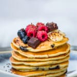 Stack of fluffy banana-chocolate chip pancakes topped with syrup and banana slices on a plate