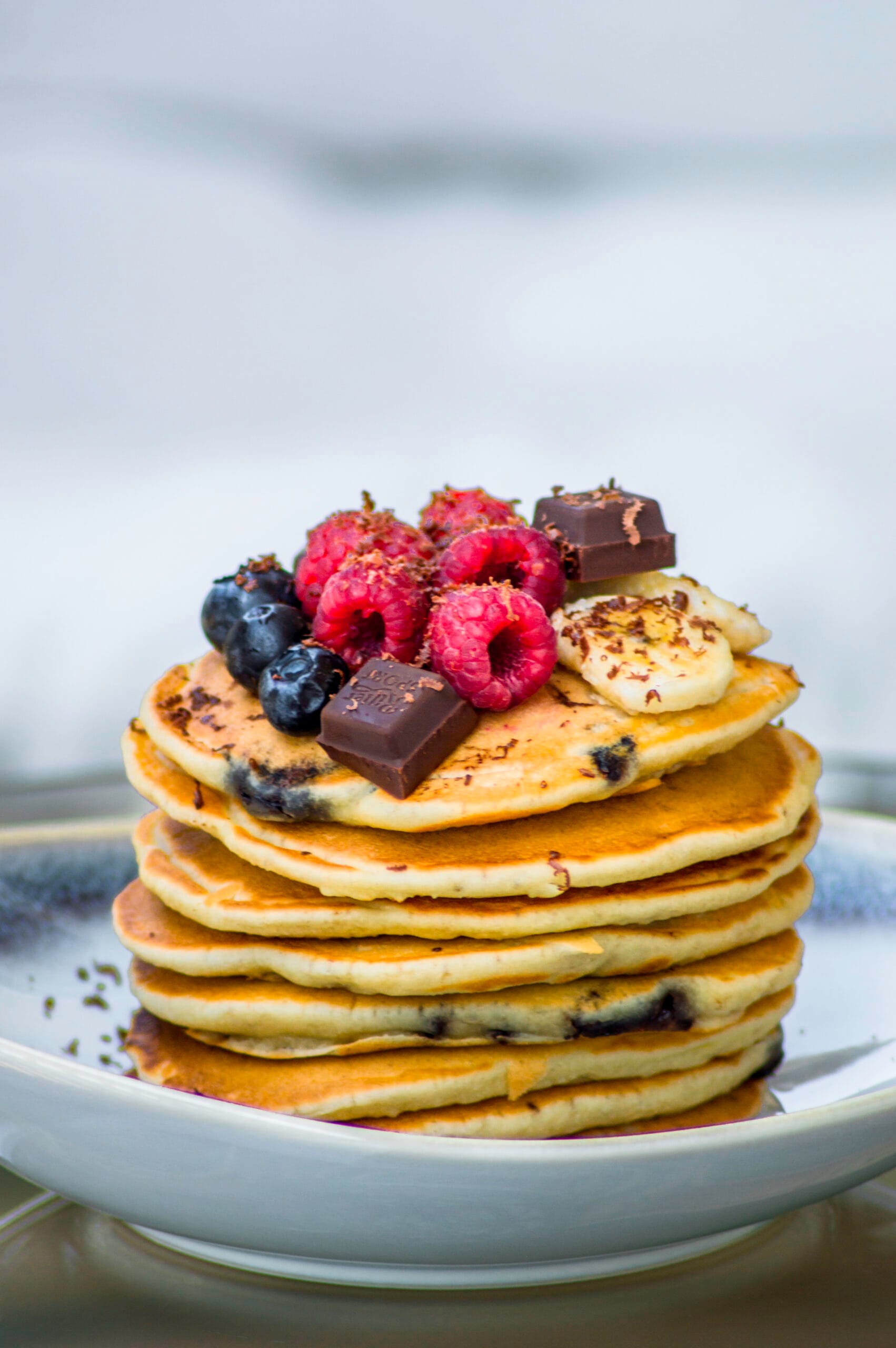Stack of fluffy banana-chocolate chip pancakes topped with syrup and banana slices on a plate