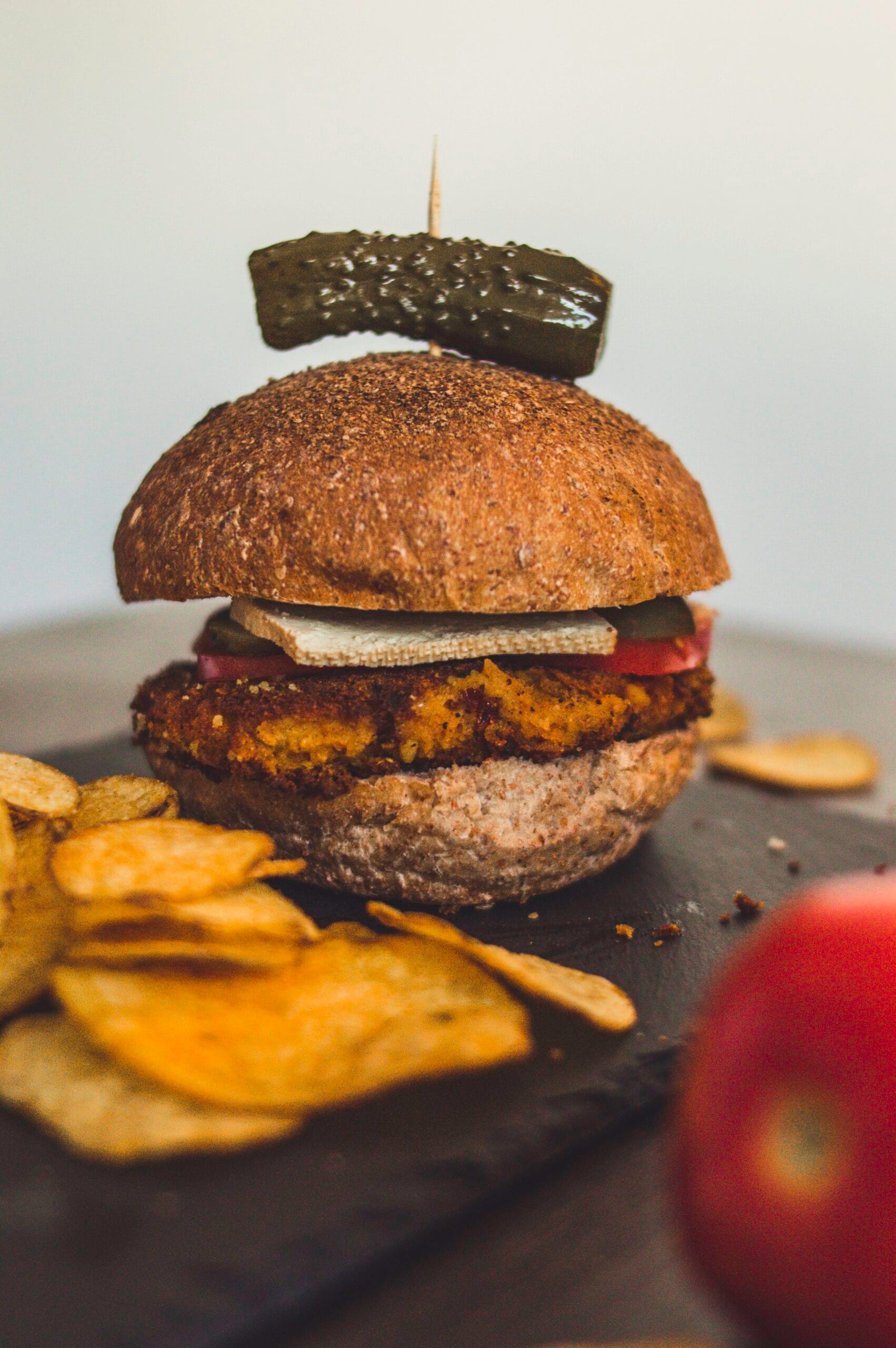 Crispy curry chickpea burgers patty on a toasted bun with lettuce, tomato, and vegan mayo served with sweet potato fries