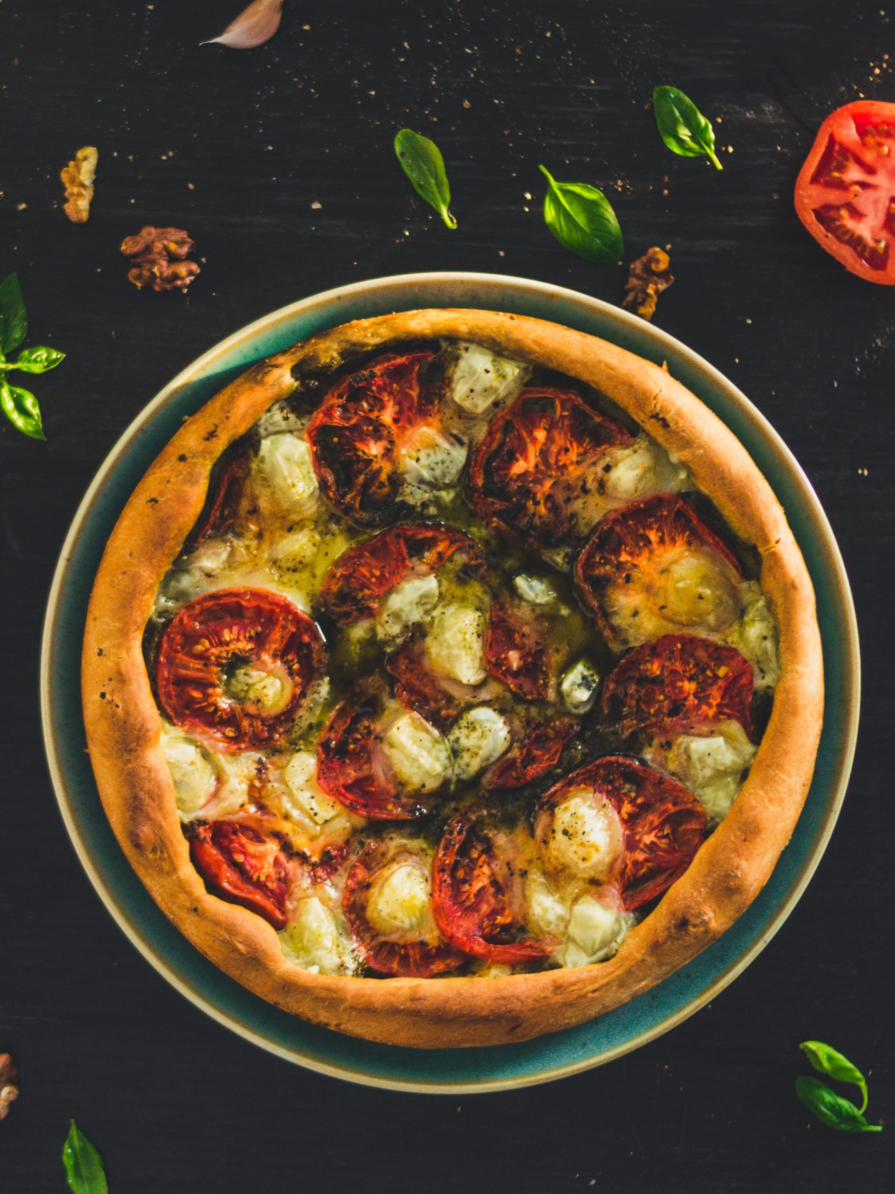 Rustic vegan tomato tart with golden crust, pesto base, and sliced tomatoes arranged in a circular pattern
