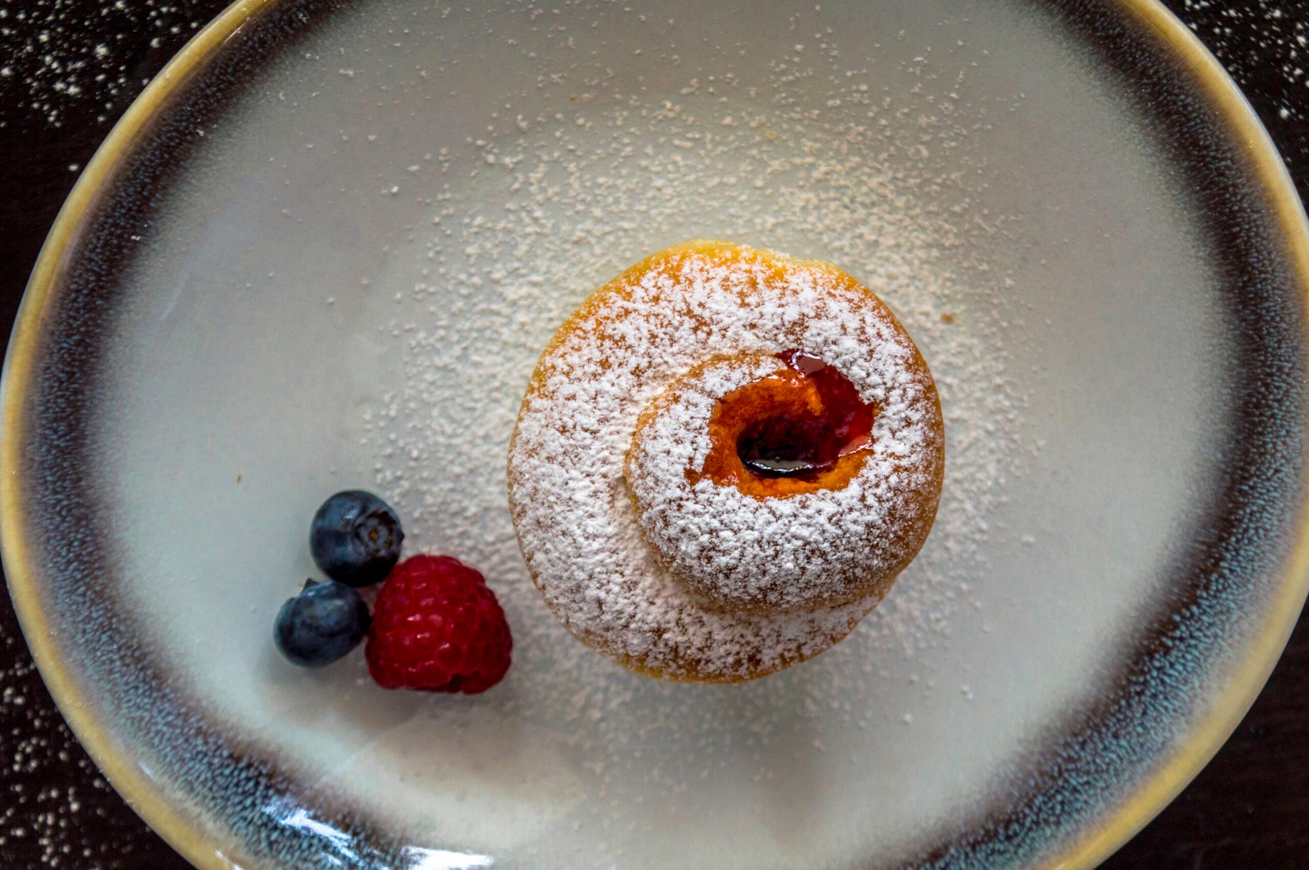 Flaky cruffins with powdered sugar and jam centers served in a muffin tin on a rustic table
