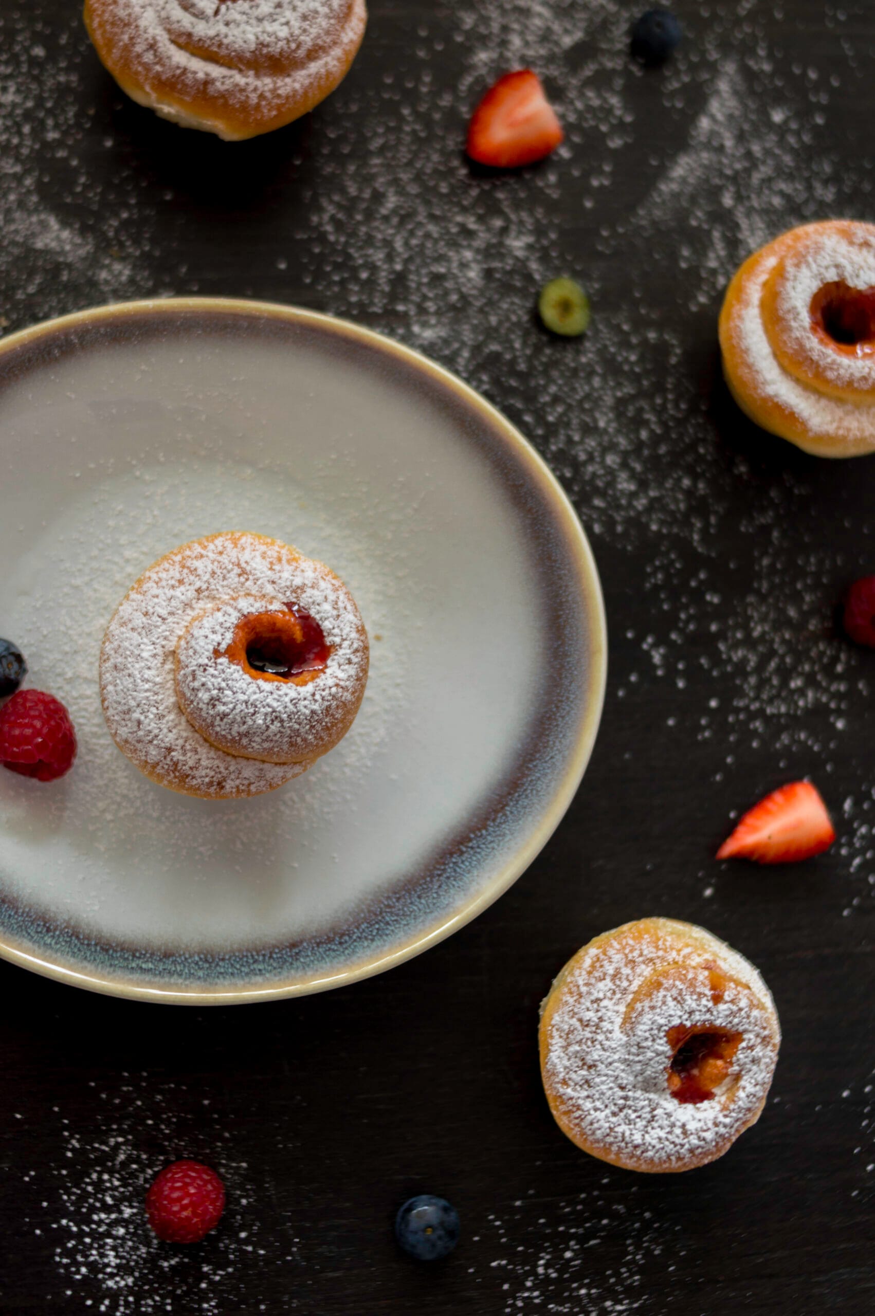 Flaky cruffins with powdered sugar and jam centers served in a muffin tin on a rustic table