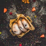 Stack of fluffy vegan donuts filled with chocolate cream, topped with powdered sugar on a cooling rack