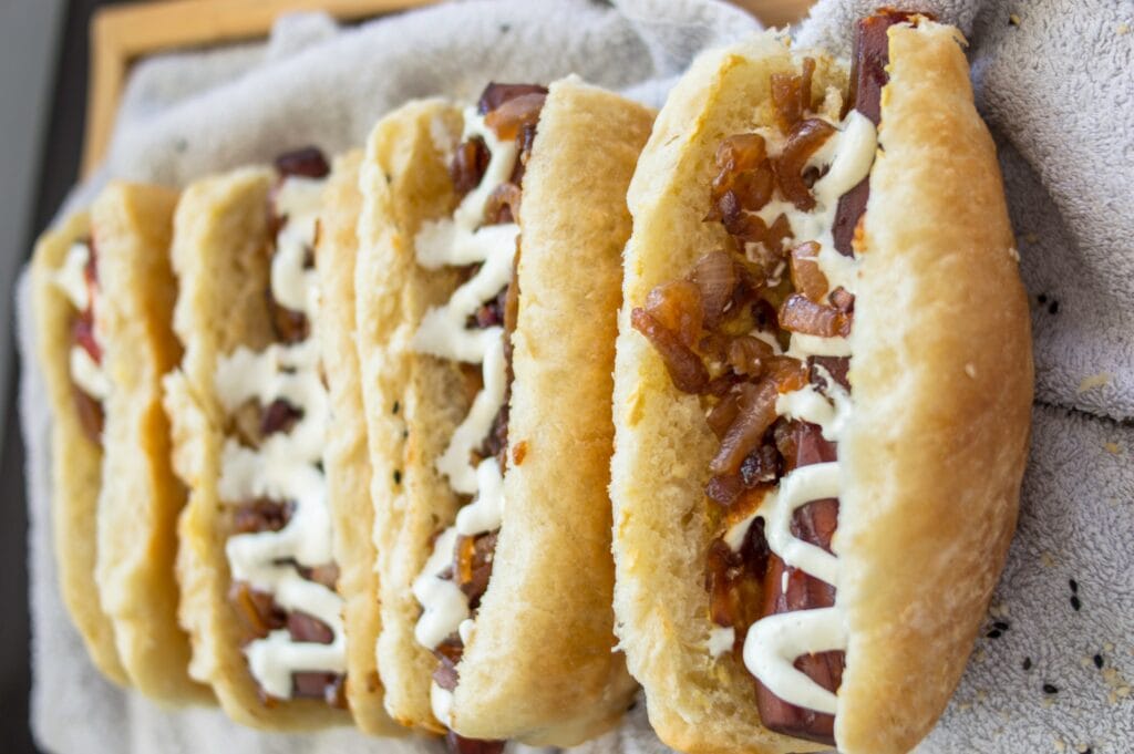 Grilled carrot hot dog in a fluffy bun with mustard, mayo, and crispy onions on top