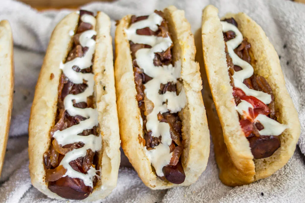 Grilled carrot hot dog in a fluffy bun with mustard, mayo, and crispy onions on top