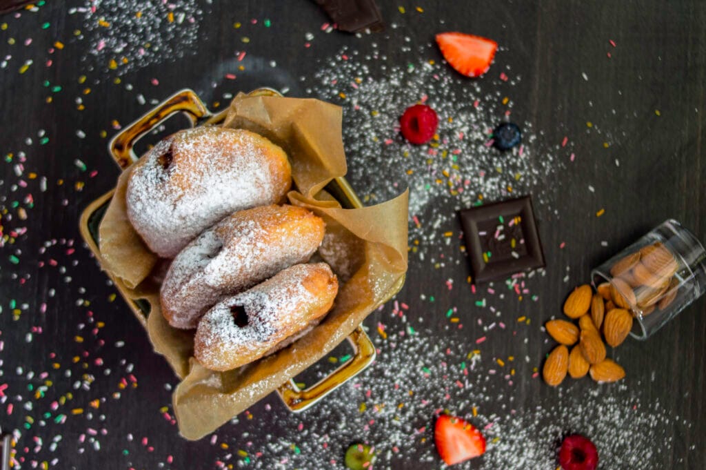 Stack of fluffy vegan donuts filled with chocolate cream, topped with powdered sugar on a cooling rack