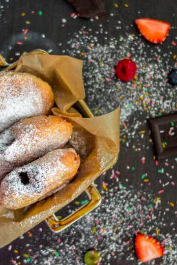 Stack of fluffy vegan donuts filled with chocolate cream, topped with powdered sugar on a cooling rack