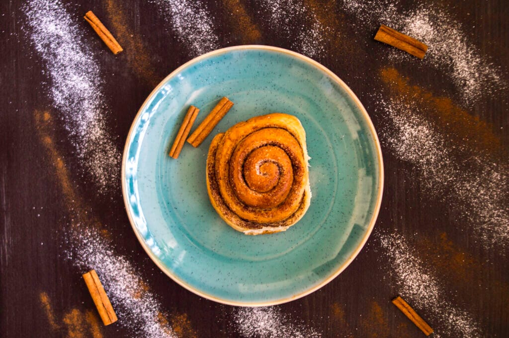 Freshly baked vegan cinnamon rolls with icing drizzle in a baking dish