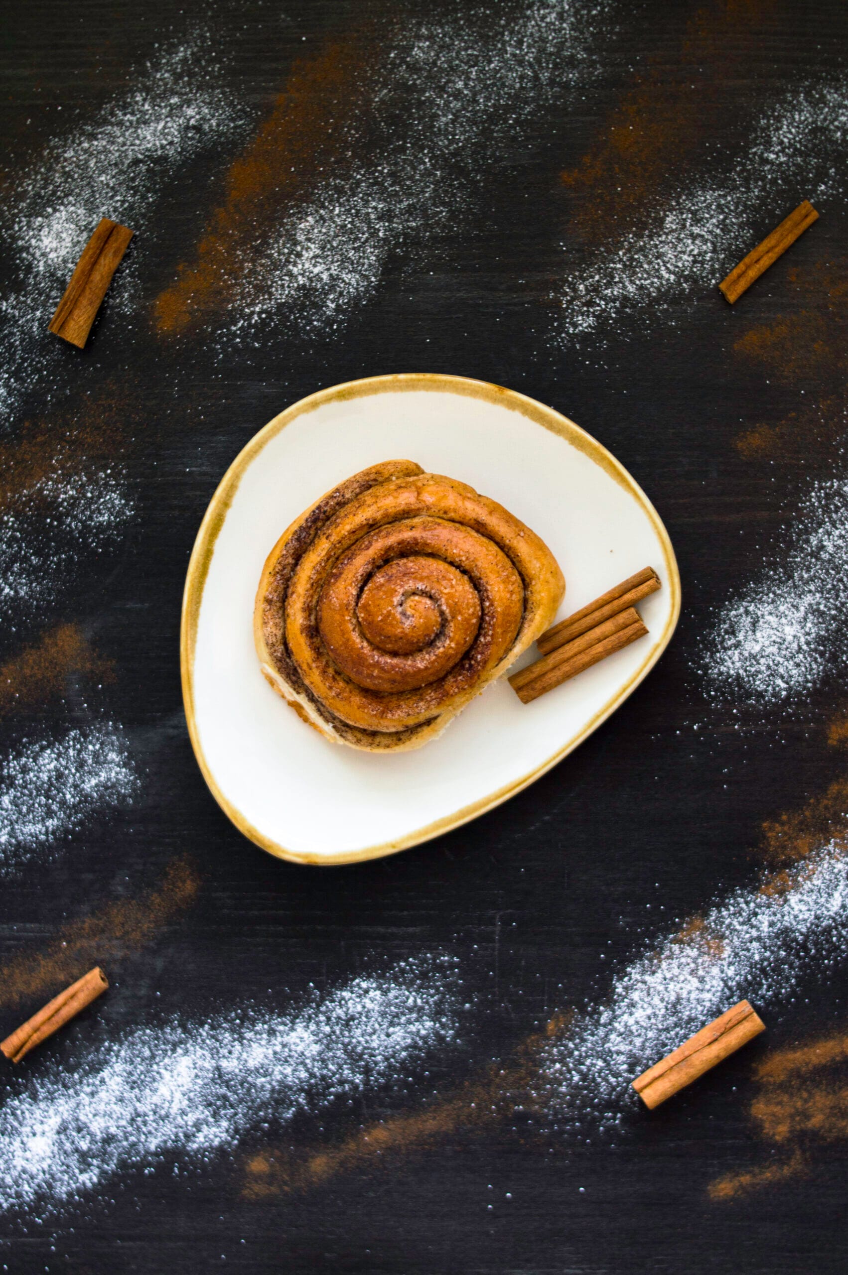 Freshly baked vegan cinnamon rolls with icing drizzle in a baking dish