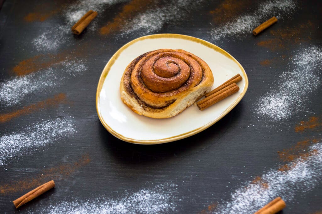 Freshly baked vegan cinnamon rolls with icing drizzle in a baking dish