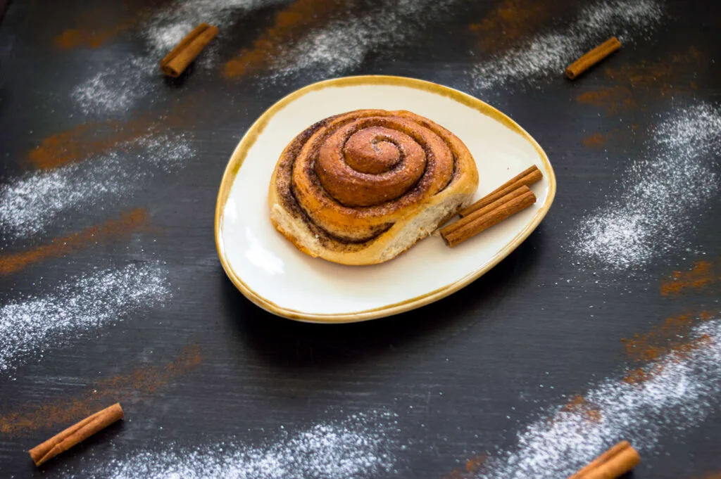 Freshly baked vegan cinnamon rolls with icing drizzle in a baking dish