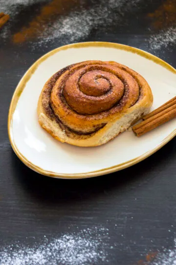 Freshly baked vegan cinnamon rolls with icing drizzle in a baking dish