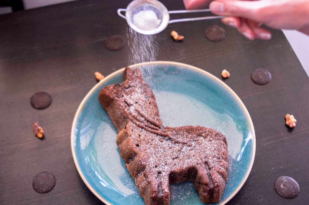 Sliced vegan breakfast loaf cake with banana, walnuts, and chocolate chunks on a wooden board