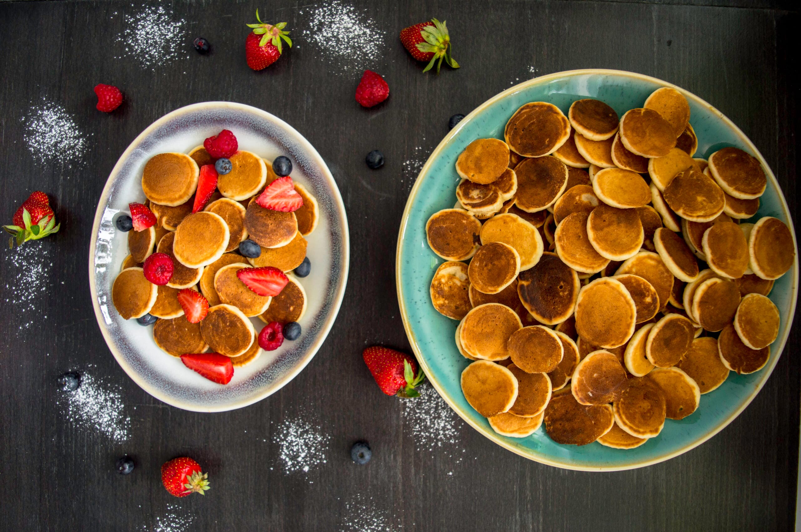 Bowl of golden mini pancakes (pancake cereal) topped with fresh fruit and maple syrup