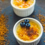 Small ramekin with vegan crème brûlée topped with a golden caramelized sugar crust and a vanilla pod beside it
