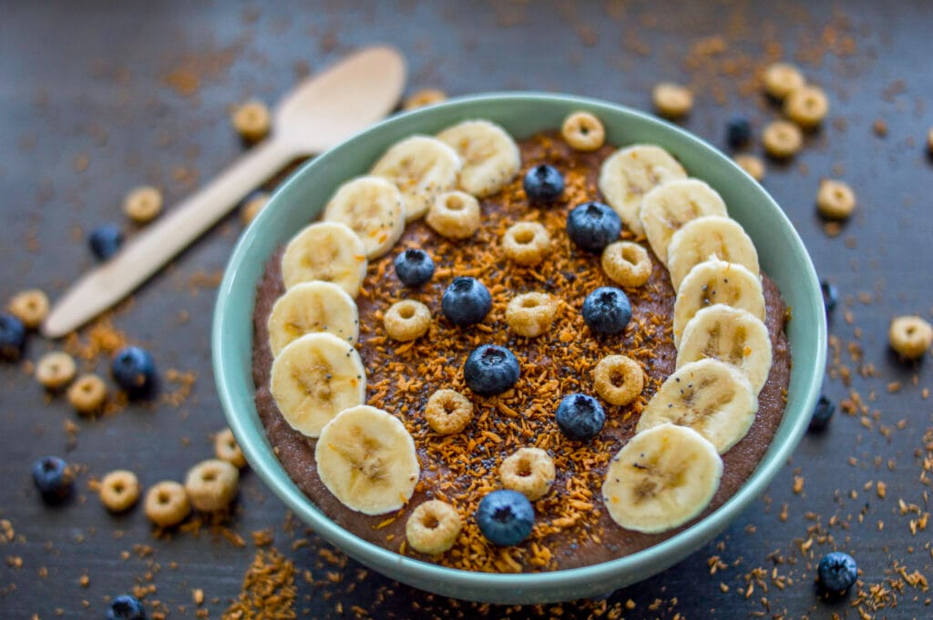 A warm chocolate semolina bowl topped with fresh berries, banana slices, and a drizzle of peanut butter