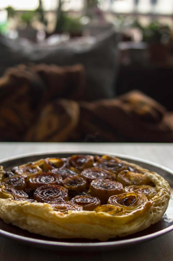 Savory Onion Tart with caramelised half-sliced onions on cheesy puff pastry golden flakey crust