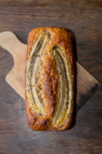 vegan banana bread with a crispy golden crust on a wooden board on a wooden background