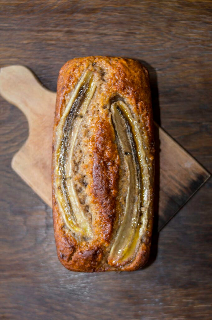 vegan banana bread with a crispy golden crust on a wooden board on a wooden background