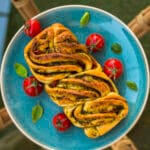 Close-up of sliced savory vegan tomato-pesto loaf with braided layers and golden crust