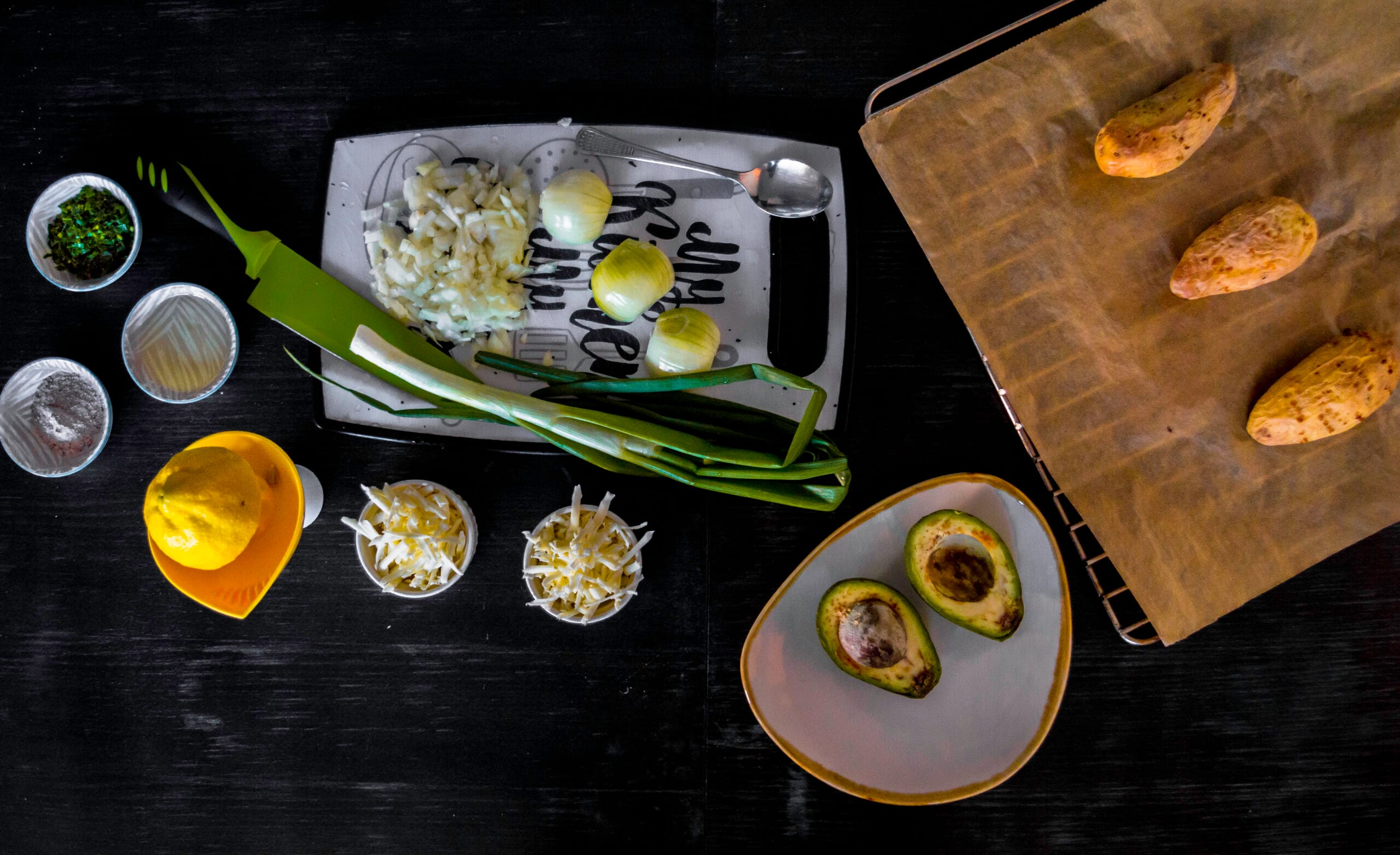 Ingredients for taco potatoes stuffed with fajita-spiced mash, melted vegan cheese on top, served with a side of creamy avocado salad.