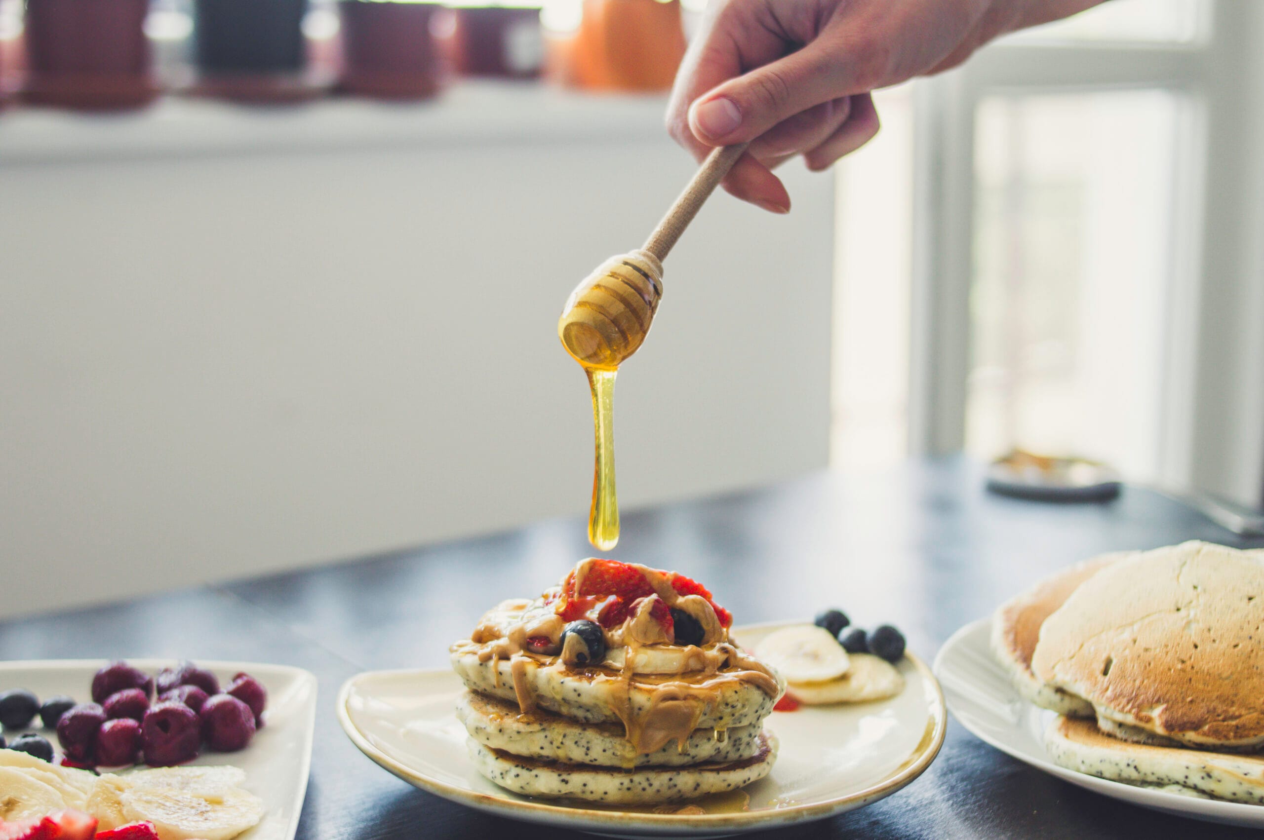 Stack of fluffy lemon poppy seed pancakes served with lemon slices and maple syrup on a white plate