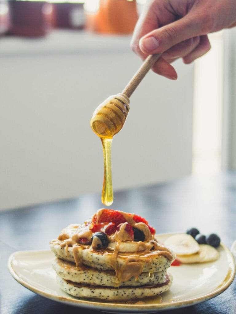 Stack of fluffy lemon poppy seed pancakes served with lemon slices and maple syrup on a white plate