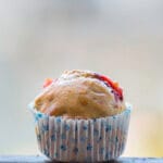 Single chocolate chip strawberry banana muffin in a blue-striped wrapper, styled with soft natural light.